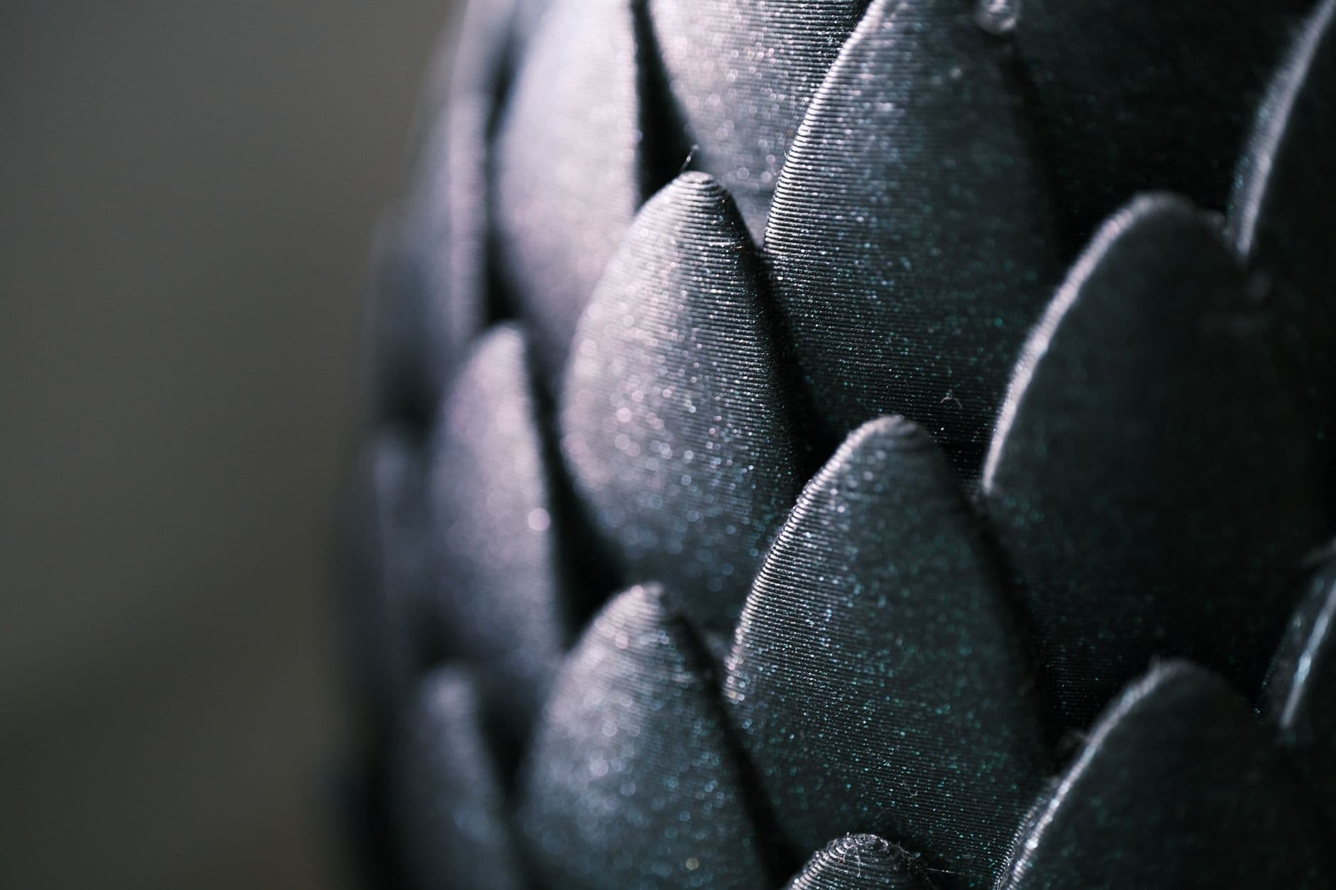 Intricate close-up of glossy black scale-like pattern with a captivating texture and shimmer.